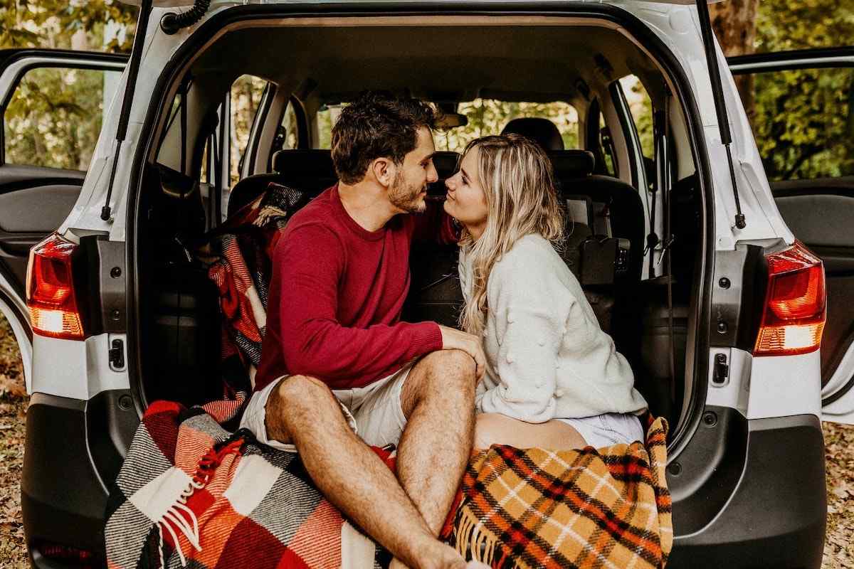 Couple sitting in the back of a van and facing in each other in love