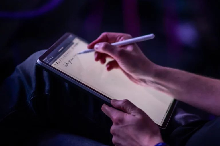 A person writing down their goals on an iPad using the goal-setting theory.