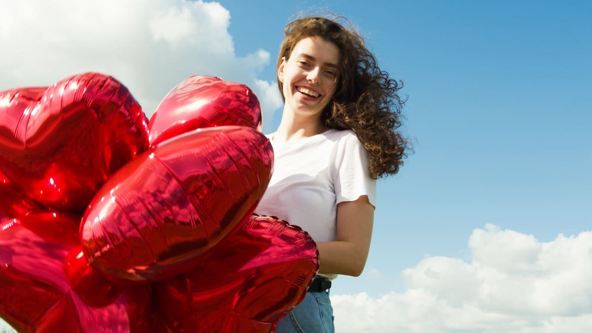 a woman holding red heart-shaped balloons