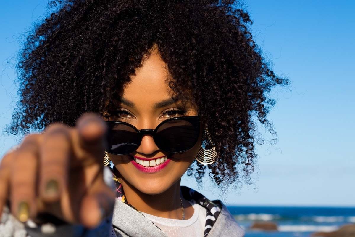 Smiling attractive black woman in nature pointing at camera