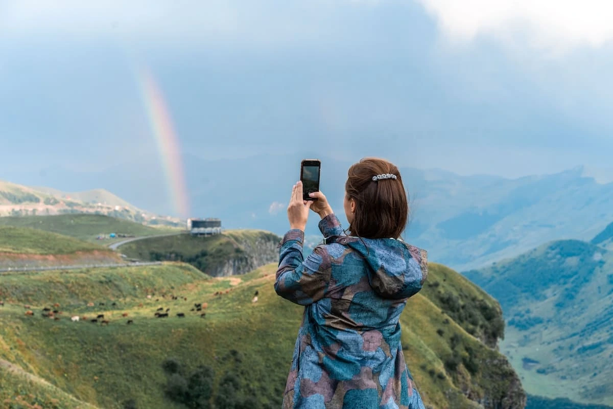 Woman taking a picture of a rainbow with her mobile phone