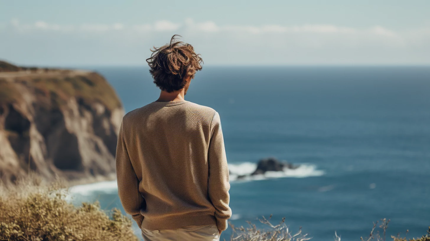 A man standing at the edge of a cliff overlooking the sea