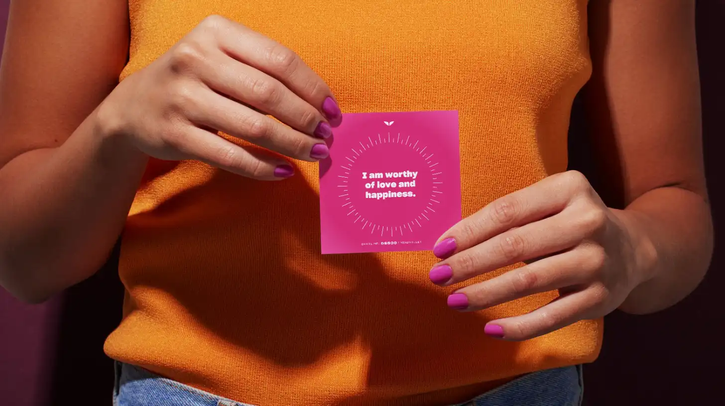 A woman holding a card from a deck of self-love affirmations