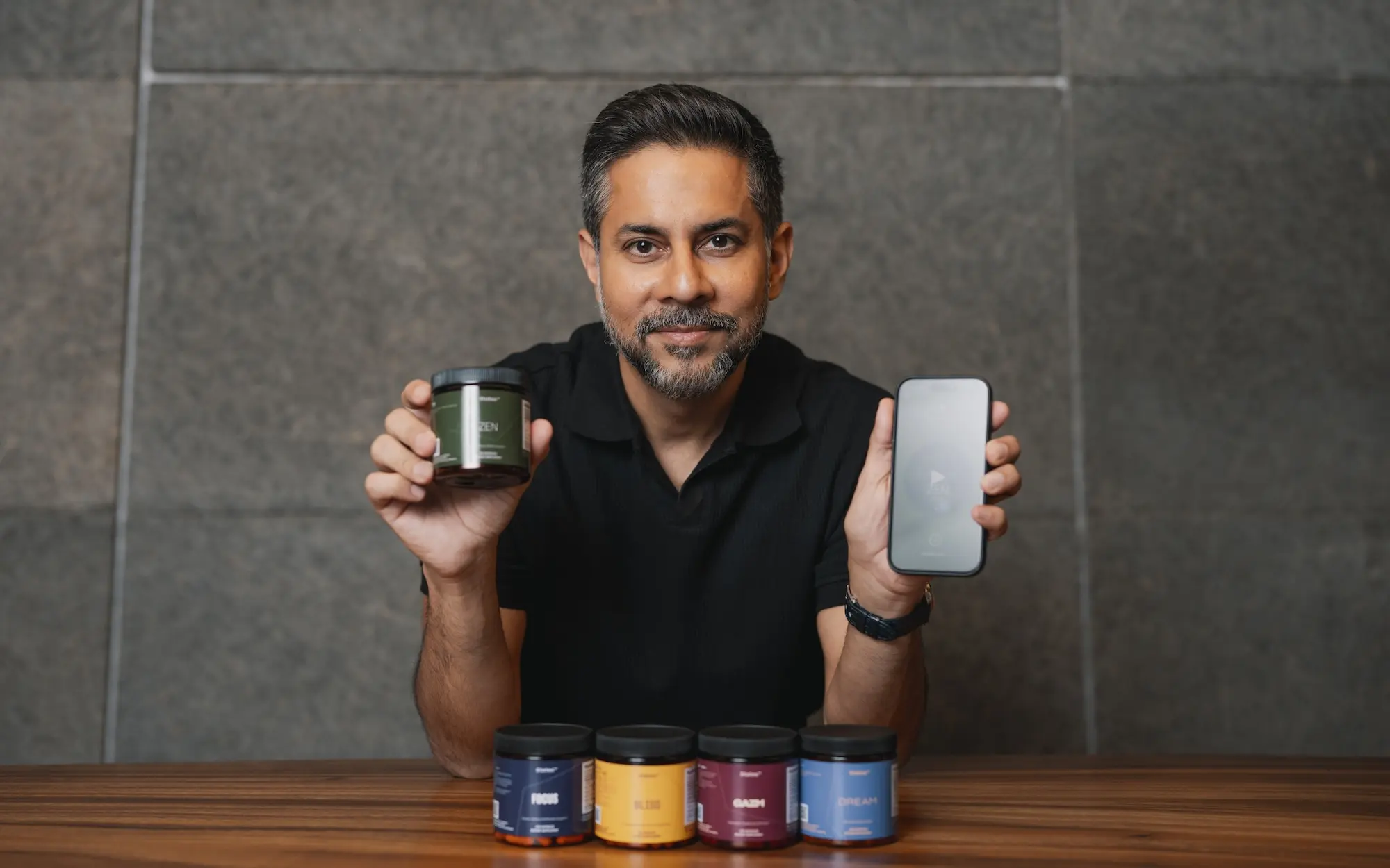 Vishen, founder and CEO of Mindvalley, with bottles of the Mindvalley States