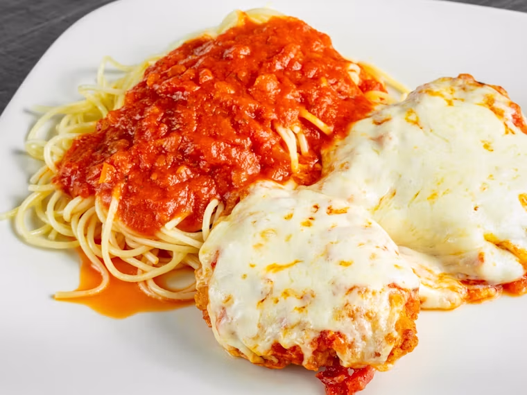 Chicken parmigiana with melted cheese over pasta