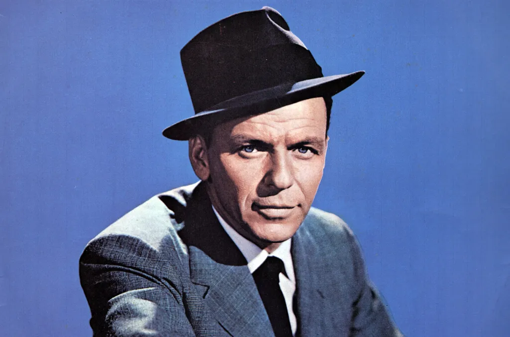 Frank Sinatra portrait circa 1960 wearing a fedora and suit against a blue background