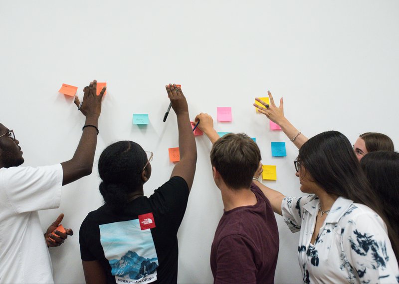 Teens putting post-it notes on wall