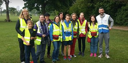 Group of adults and children in green area wearing hi-vis jackets