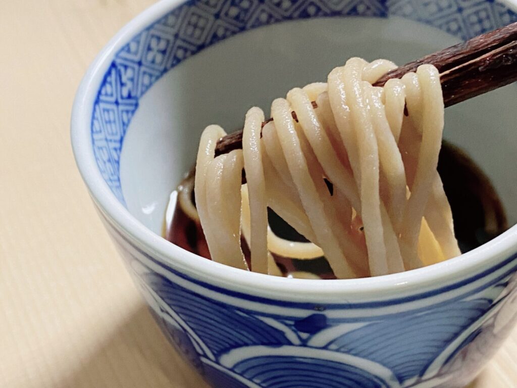 ゆでたおこめんを麺つゆにつけている写真