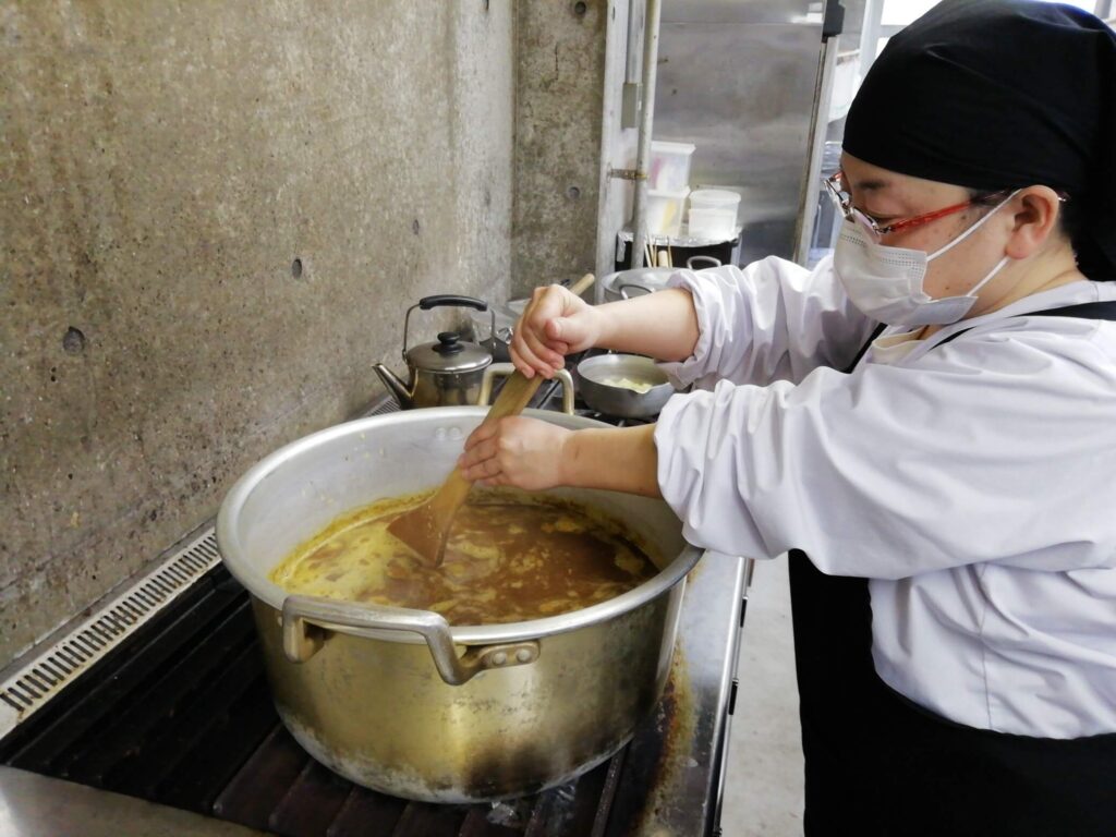 スタッフが鍋に入ったカレーをしゃもじで混ぜている