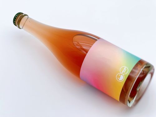 白い床に横倒しに置かれた瓶には、虹色のラベルが貼られている。とてもキュートな色合いで甘い香りが漂ってくる感じがする。