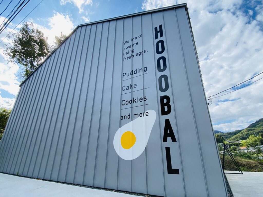 お店の外壁にプリントされた店名「HOOBAL We make sweets using fresh eggs.Pudding,Cake,Cookies,and more」と書かれている