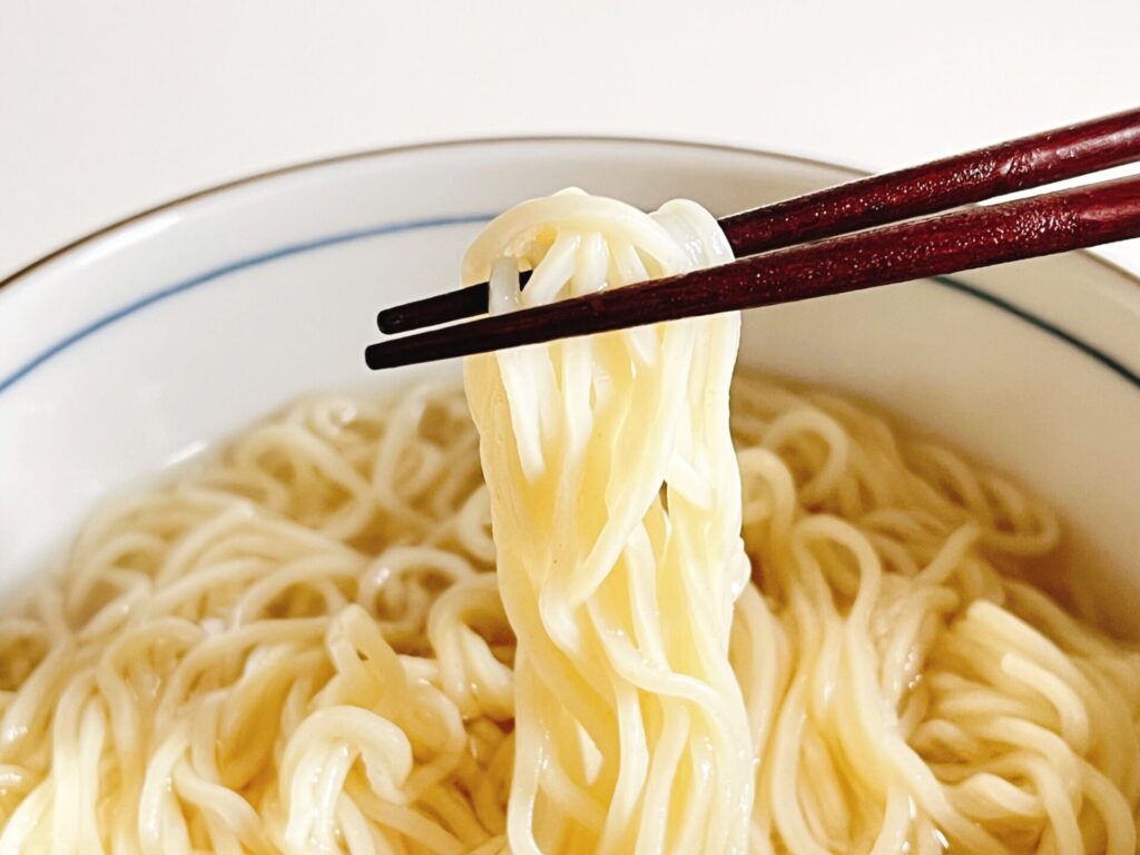 ラーメンを箸でつかんでいる様子の写真