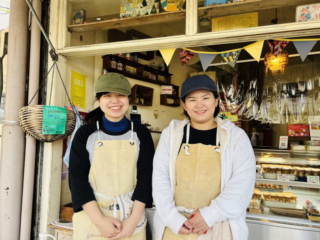 笑顔のスタッフが二人並んで店先に立っている写真