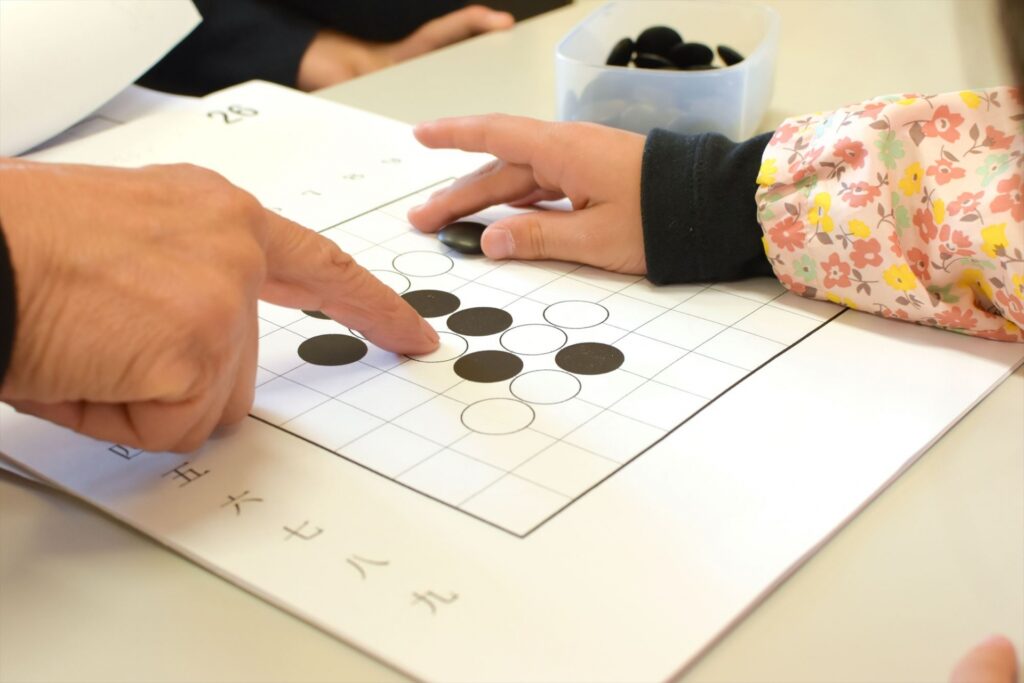 大人と子供が囲碁を打っている手元を映した写真