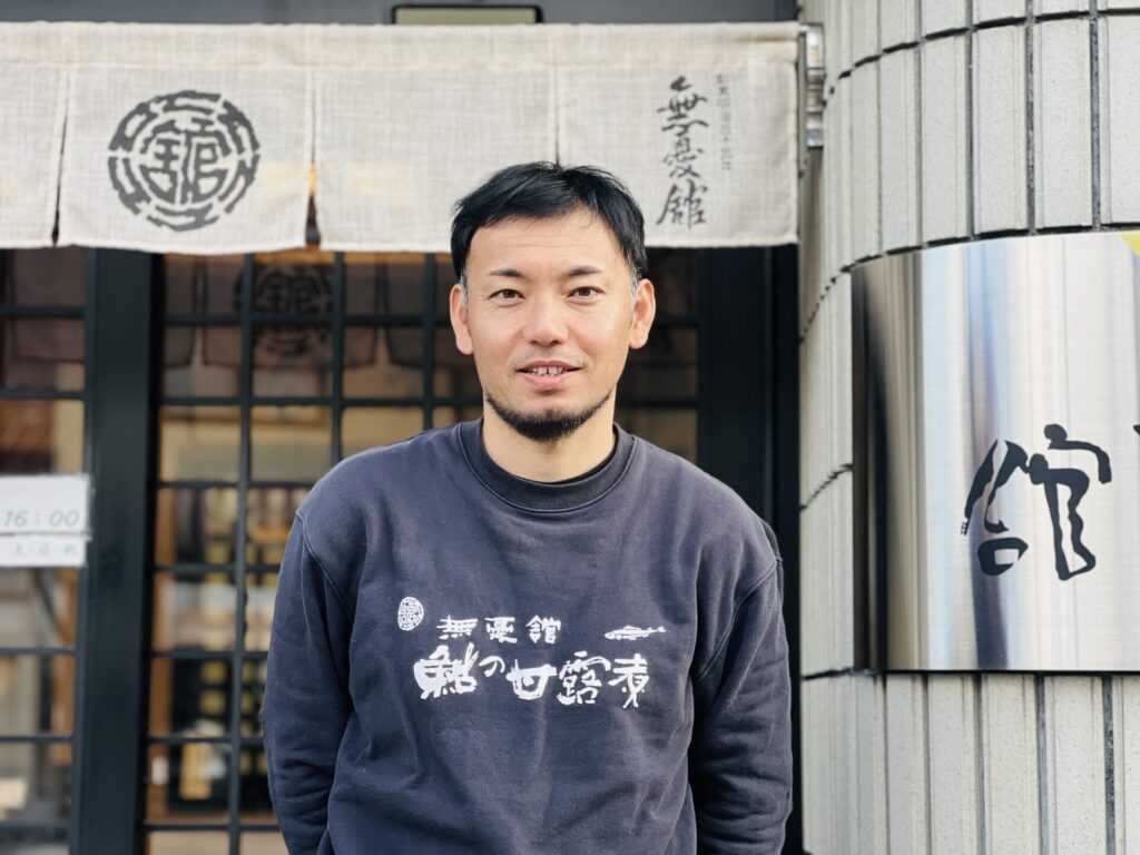 店舗前に立ってインタビューを受ける無憂館の5代目星野 裕さん