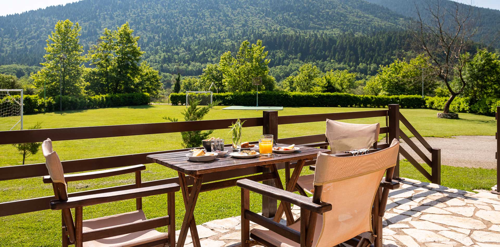 A table and chairs on a patio overlooking a field and mountains.