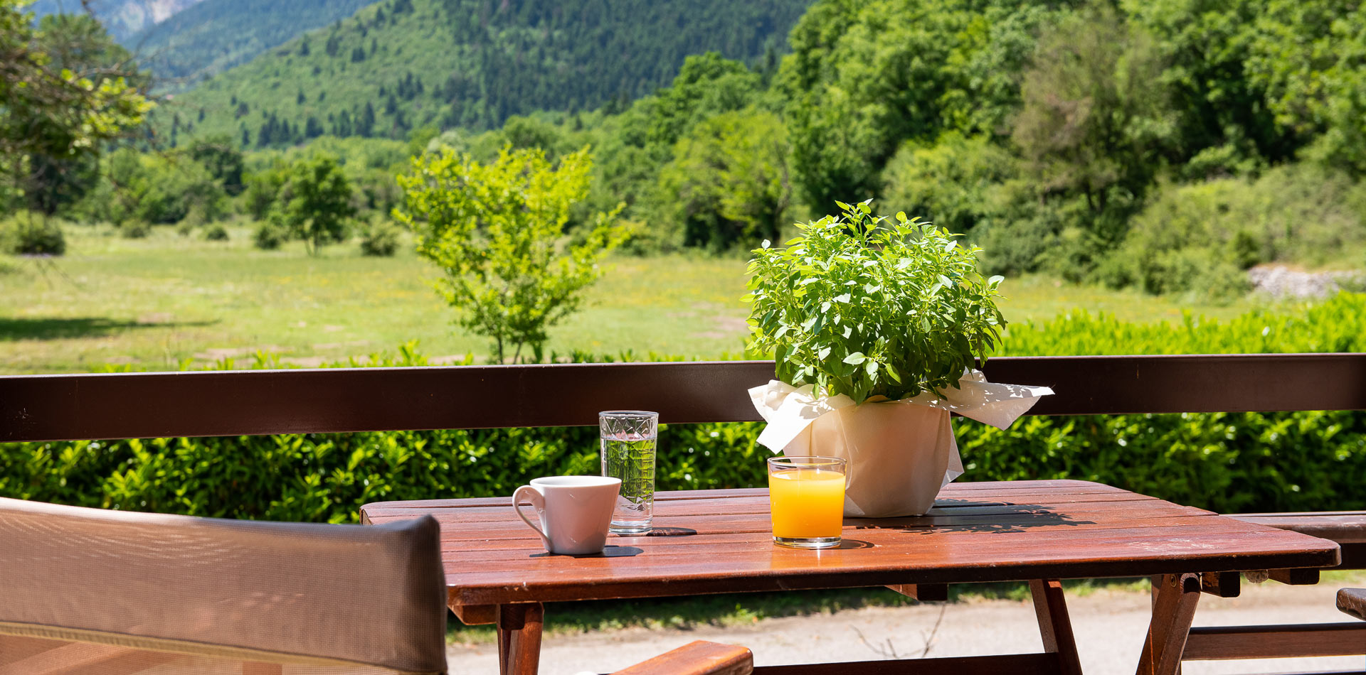 Ένα ξύλινο τραπέζι με ένα φλιτζάνι καφέ και ένα ποτήρι χυμό πορτοκαλιού επάνω του.