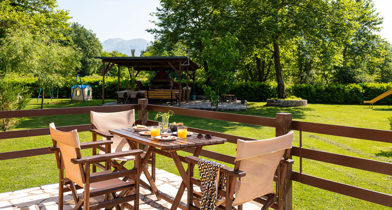 A table and chairs on a patio overlooking a field and mountains.