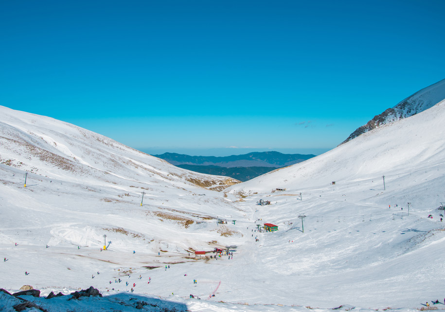 Ski resort in the mountains with skiers and snowboarders on the slopes.