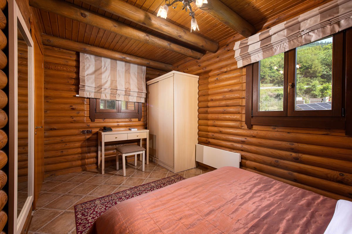 Bed, small desk and a closet in Natura Chalet bedroom