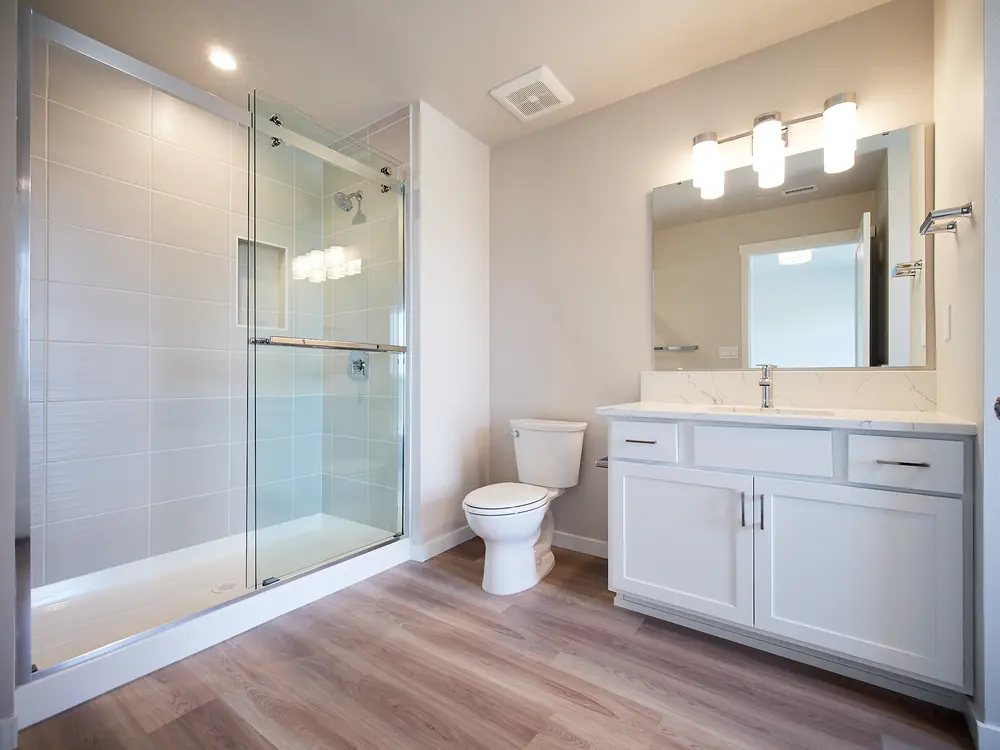 Primary Bathroom with quartz counters and tile wall shower with glass door.
