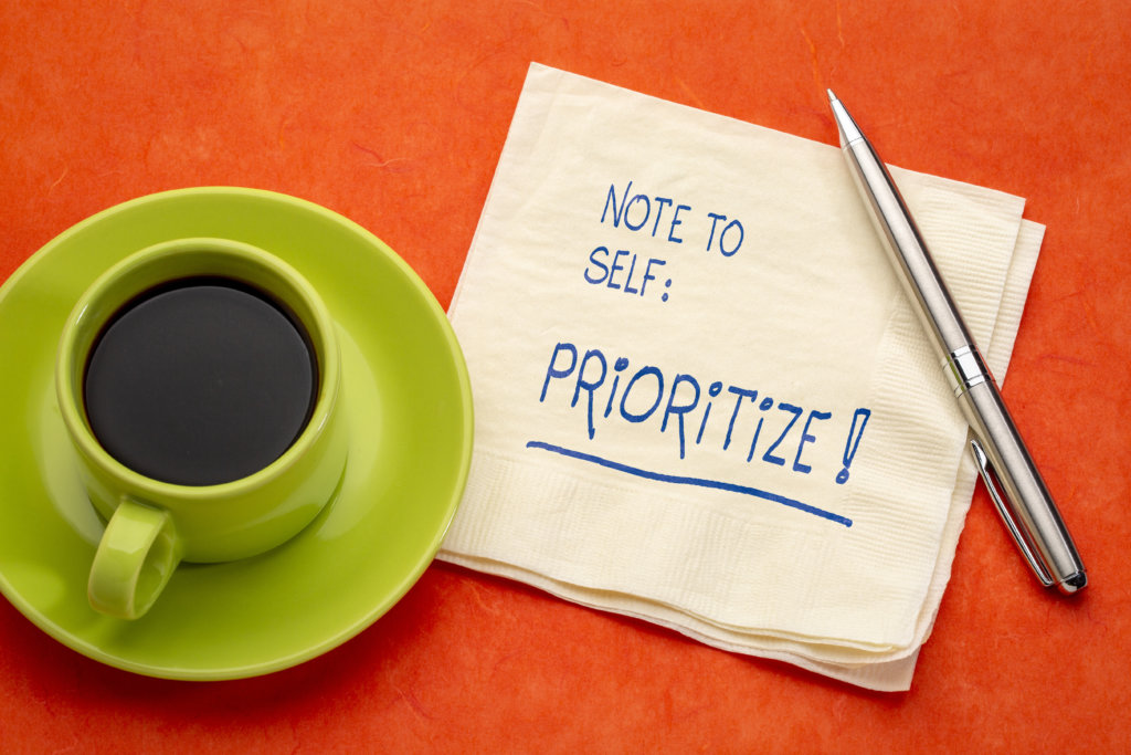 Imagem mostra uma xícara com café e, ao lado, uma mensagem escrita no guardanapo "nota para mim: priorizar!". Prioridades são importantes na hora de saber como estudar.