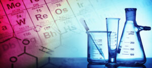 Recipientes de vidro de química com imagem de tabela periódica ao fundo para representar a disciplina de Química na Uerj
