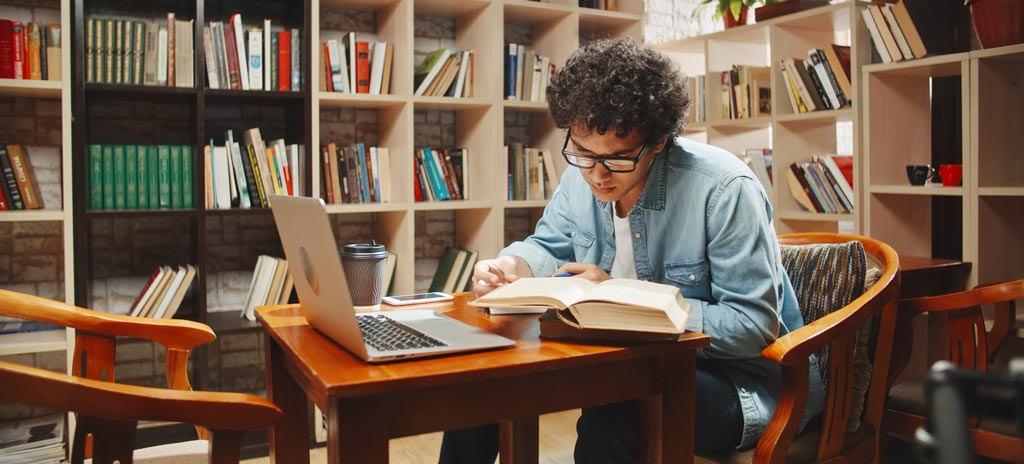 Aluno estudando em biblioteca - questões de literatura