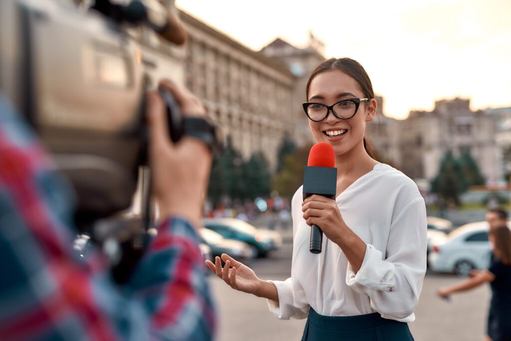 Jornalista de TV apresentando as notícias ao ar livre