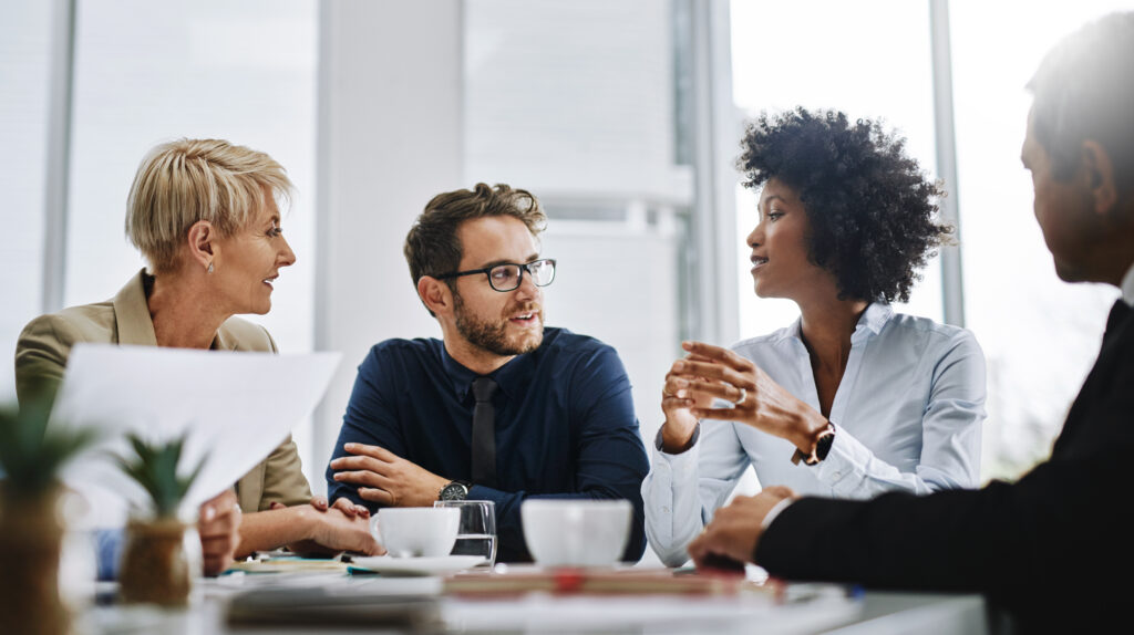 Grupo de empresários sentados juntos em uma reunião discutindo sobre relações internacionais.