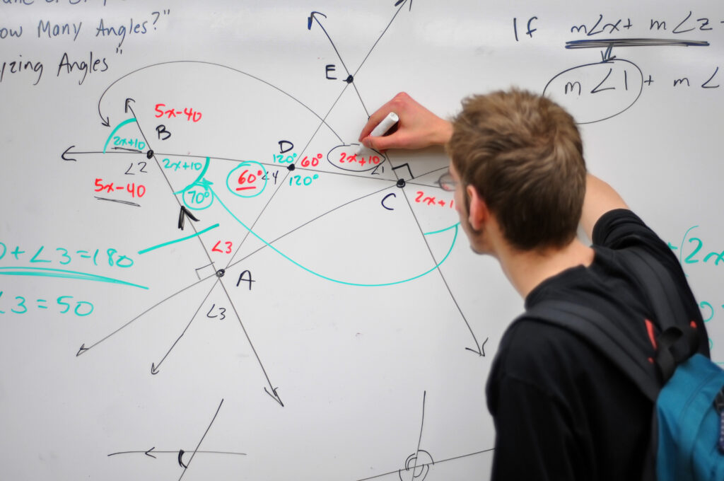 Aluno estudando matemática no quadro branco.