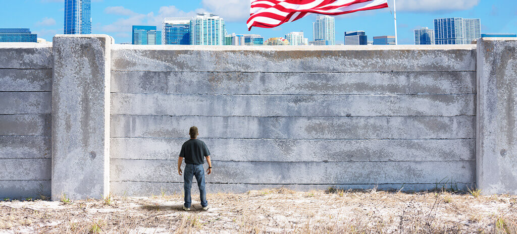Simulação de imigrante em frente a um muro nos Estados Unidos