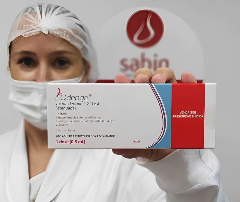 Notícias da ciência: enfermeira segurando caixa do imunizante Qdenga (TAK-003), do laboratório Takeda Pharma