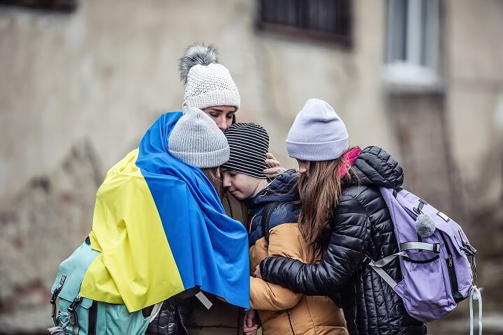 Refugiados se abraçam com a bandeira da Ucrânia