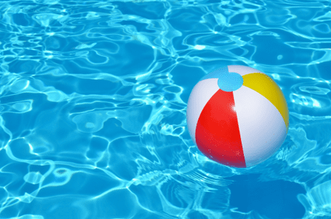 Bola de praia de plástico boiando dentro de piscina.