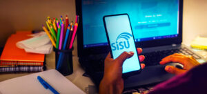 Pessoa segurando celular com site aberto do sisu 2024 instituições cursos e vagas disponíveis