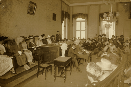 Mulheres reunidas no Congresso da Federação Brasileira pelo Progresso Feminino em 1922. Mulheres sentadas reunidas em plenário falando sobre o voto feminino no Brasil.