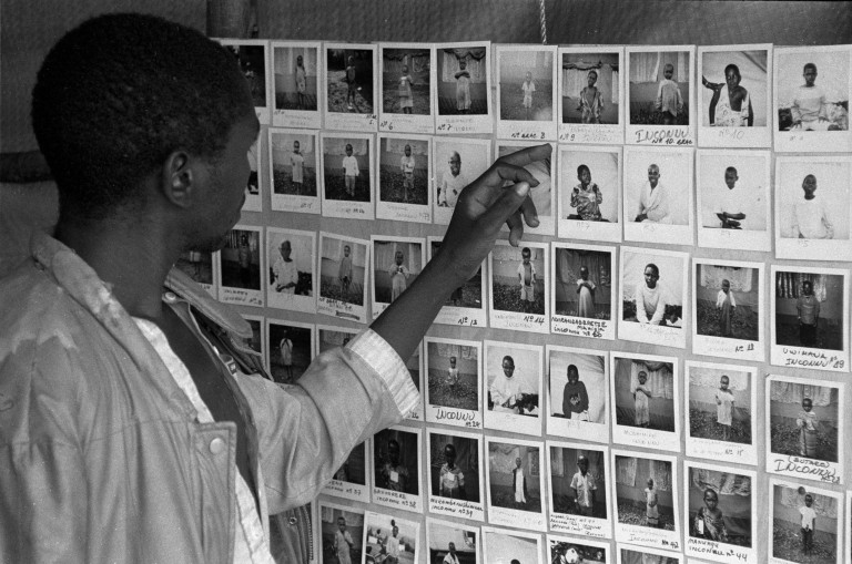 Um pai procura por fotos de seu filho desaparecido durante o genocídio em Ruanda
