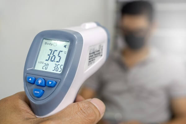 Mão segurando Termômetro infravermelho medindo a temperatura de uma pessoa