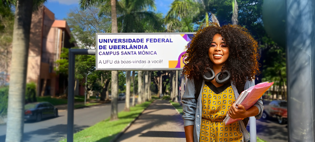 Estudante sorridente em frente ao Campus Santa Mônica da Universidade Federal de Uberlândia (UFU)