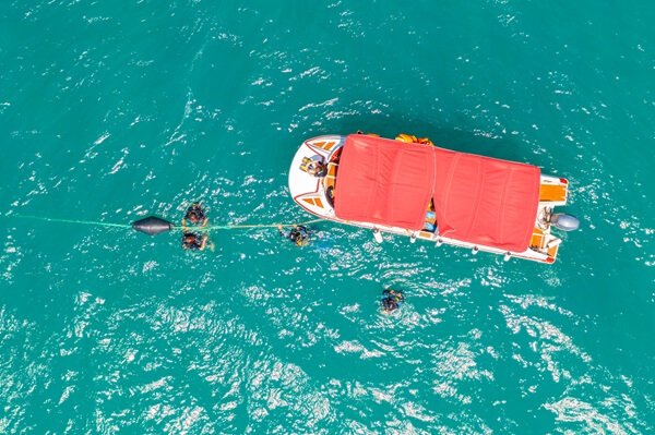 Mergulhadores oceanógrafos nadando perto de barco no mar