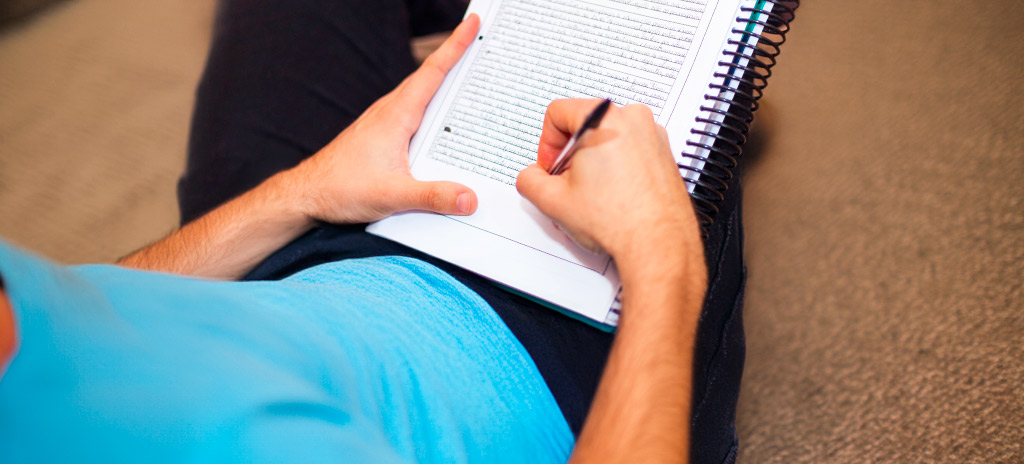 Estudante escrevendo texto em caderno conforme quantas linhas tem a redação do Enem