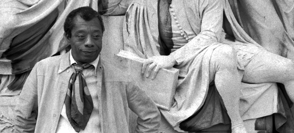 Foto de James Baldwin em frente ao Albert Memorial ao lado da estátua de Shakespeare