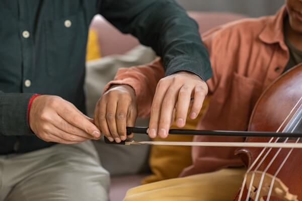 Professor de música ensinando aluno a tocar violoncelo
