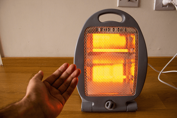 Mão de uma pessoa perto de um aquecedor elétrico para se esquentar