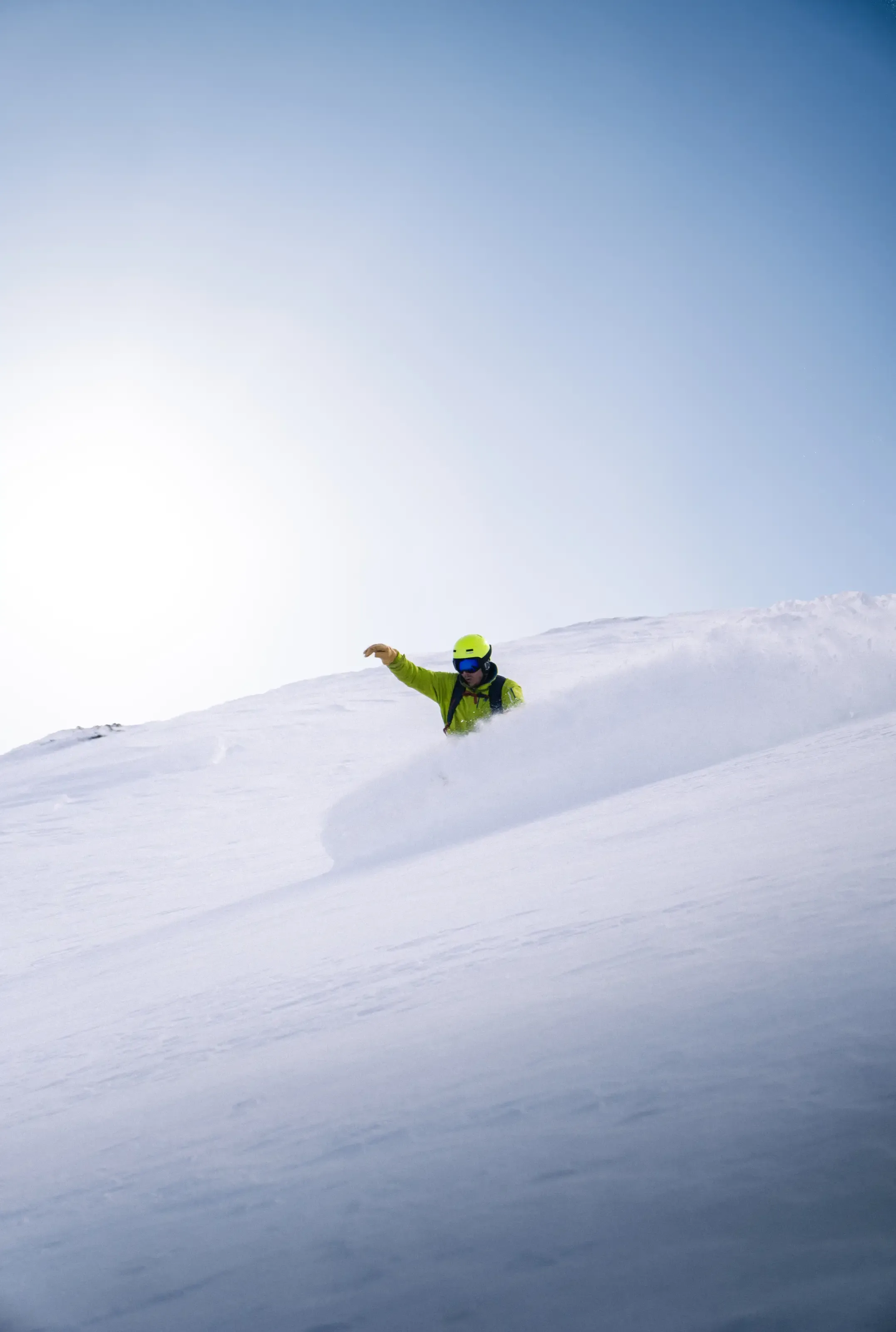 Un snowboarder effectue un slash de neige dans la poudreuse a Gourette