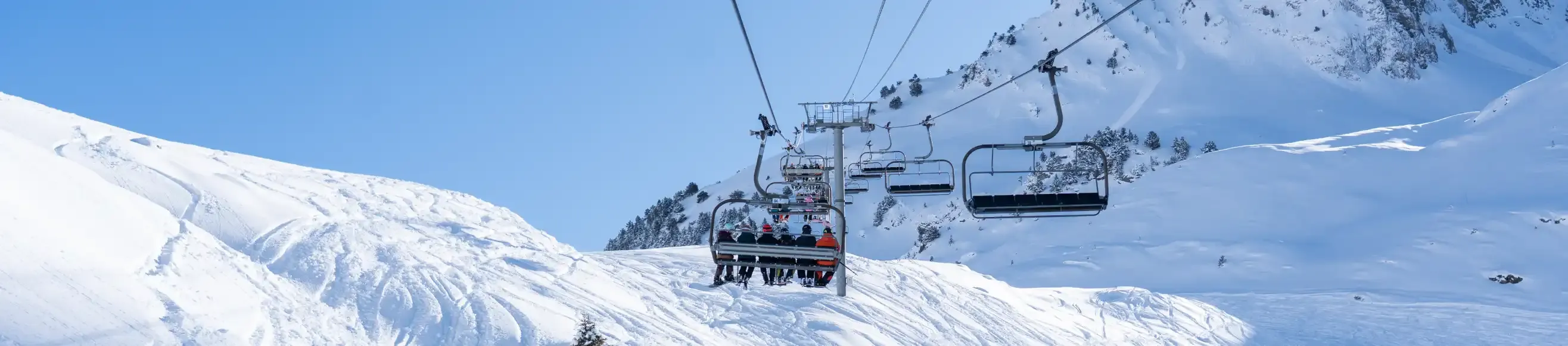 View of four people on a chairlift at the Grand Tourmalet, sun and snow