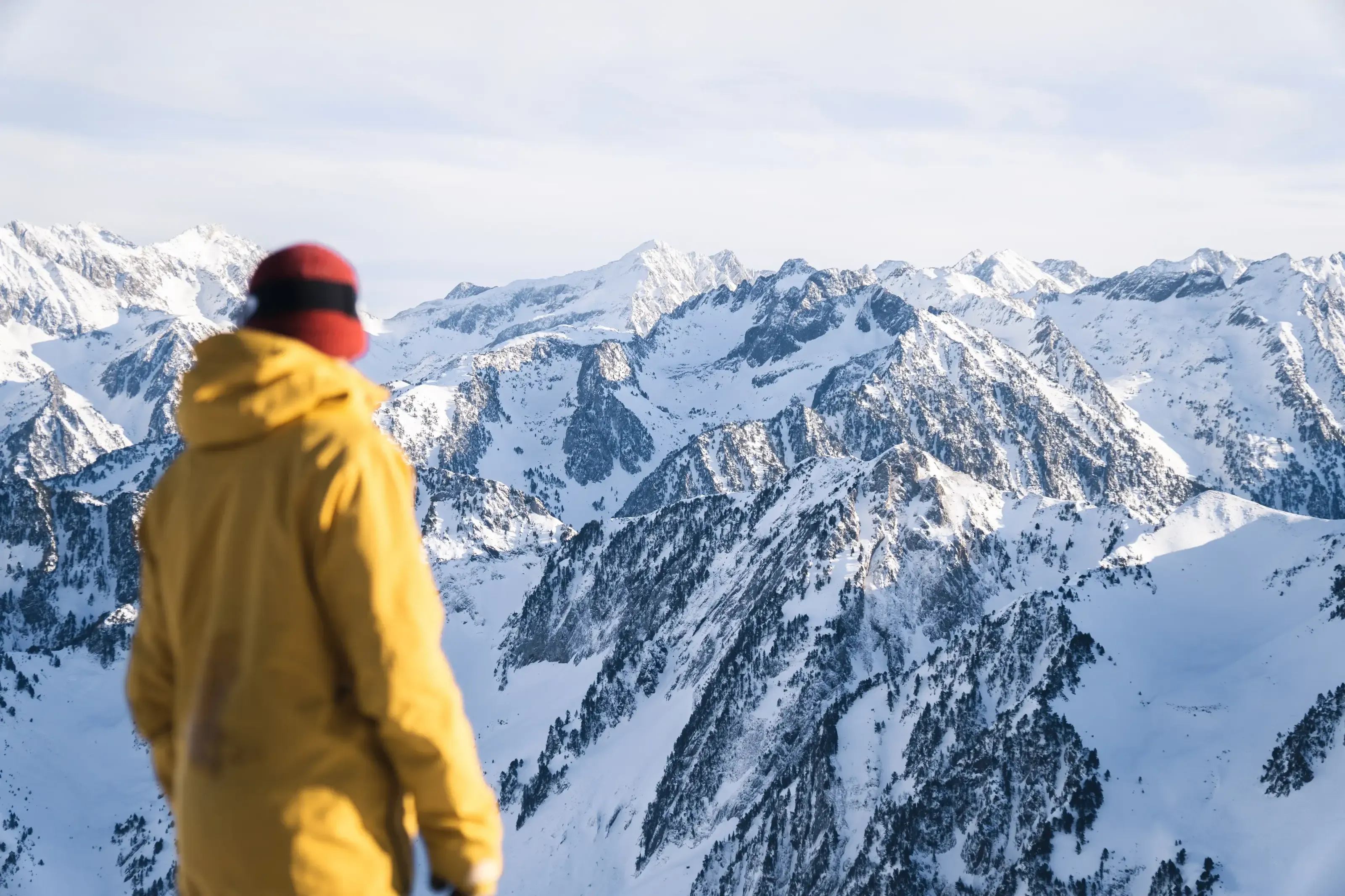 Un snowboarder contemplant les hauts sommets Pyrénéens depuis le sommet du domaine.