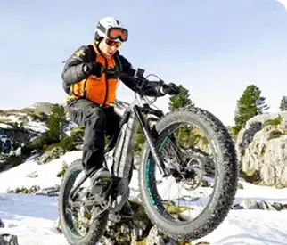 Un moniteur de VTT Fatbike faisant une roue arrière dans la neige.